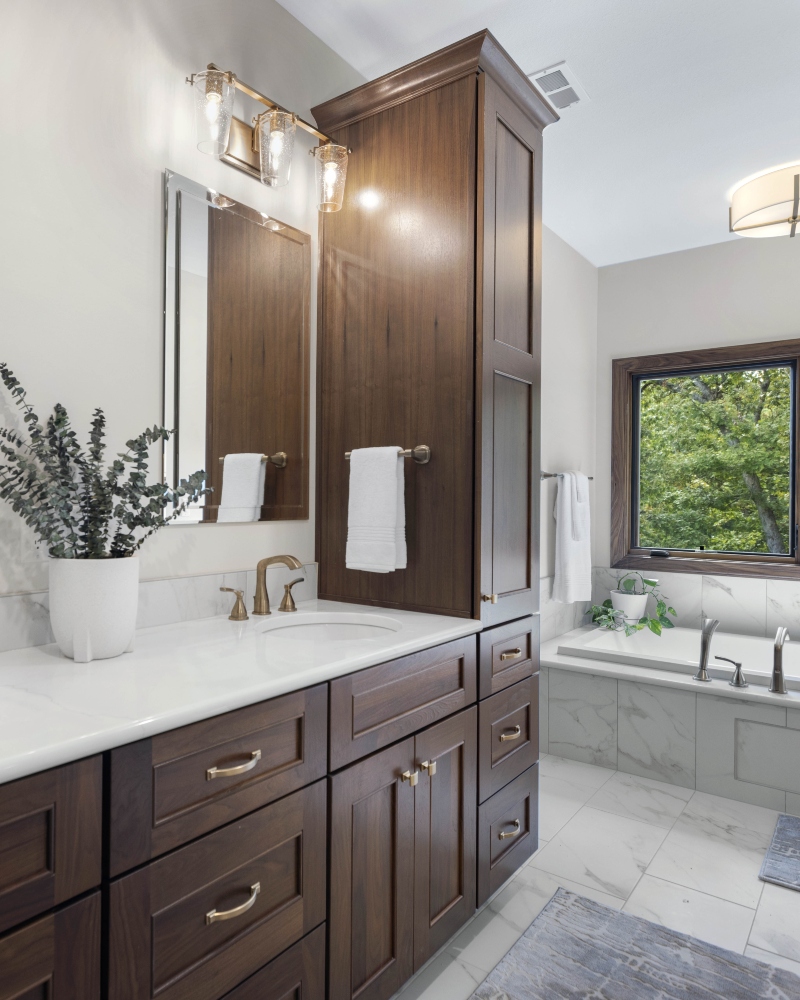 Custom bathroom with dark wood vanity cabinetry, white countertops and soaking tub by Ragan Cabinets.