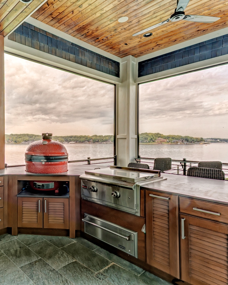 Custom outdoor kitchen with wood cabinetry, stainless appliances and lake view by Ragan Cabinets at Lake of the Ozarks.