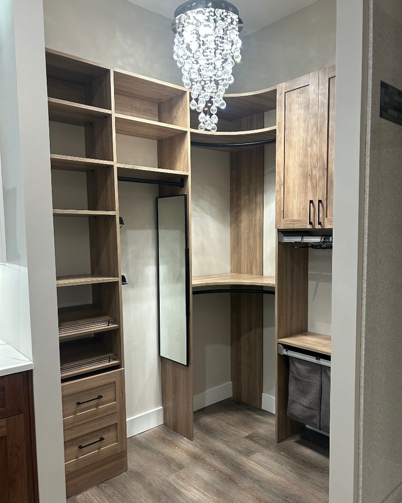 Custom walk-in closet with wood shelving, built-in drawers, hanging storage and integrated cabinetry by Ragan Cabinets.