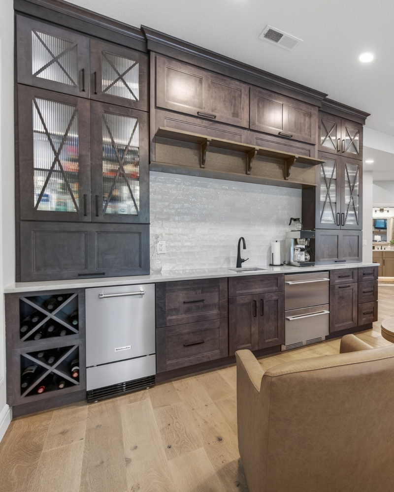 Custom wet bar with dark wood cabinetry, wine storage, beverage refrigeration and bar sink by Ragan Cabinets.
