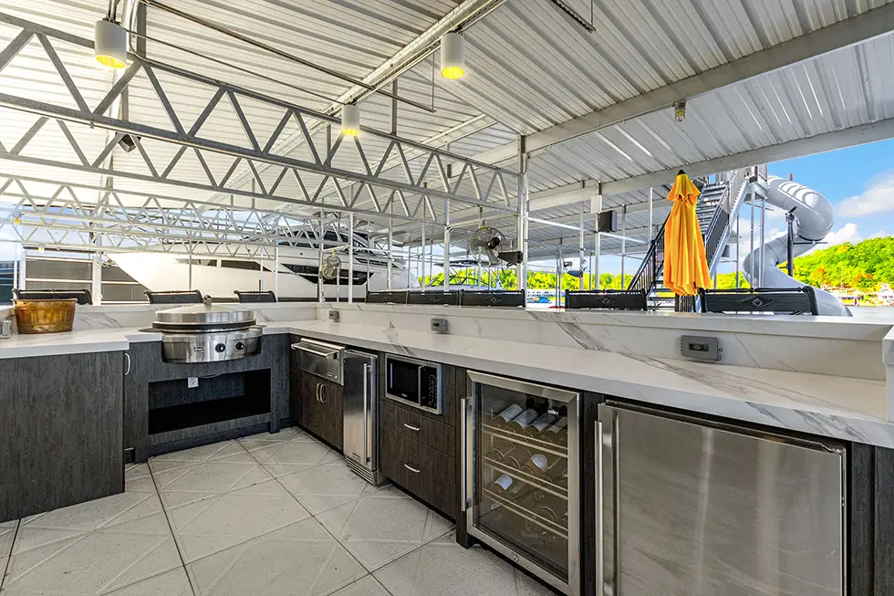 Custom Lake of the Ozarks outdoor kitchen with built-in cabinetry, stone countertops, stainless appliances and waterfront views by Ragan Cabinets.