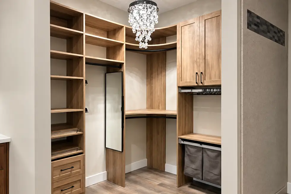 Custom walk-in closet with warm wood cabinetry, open shelving, hanging storage, drawers, built-in hamper and full-length mirror by Ragan Cabinets.
